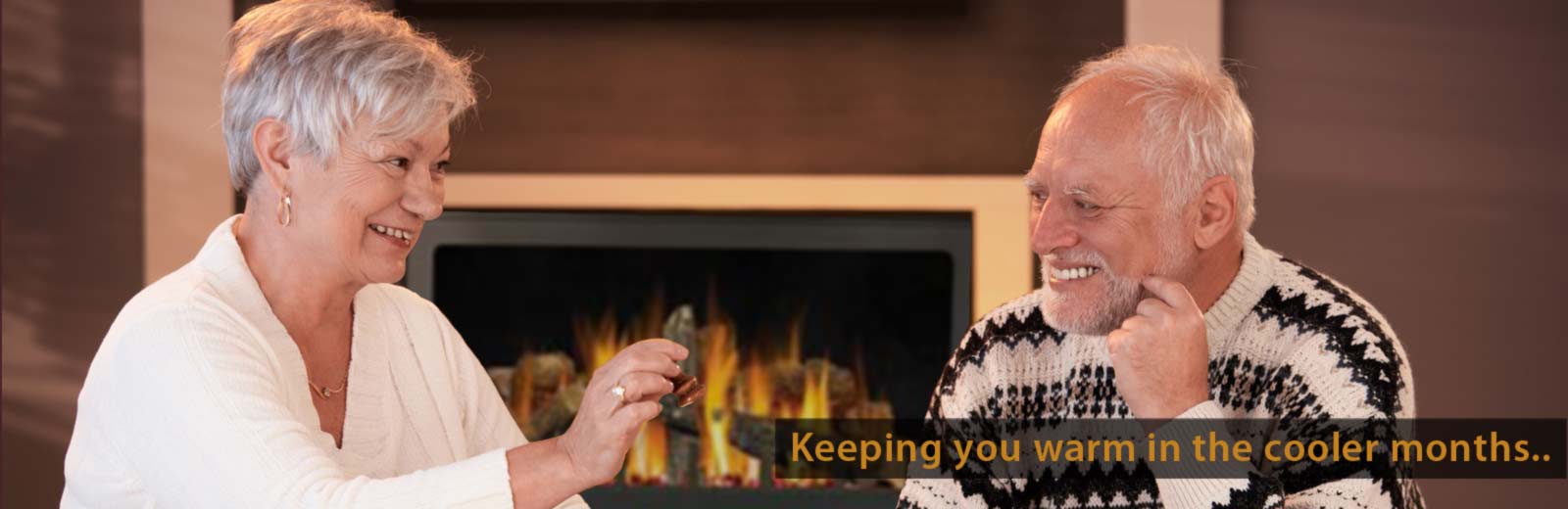 Image of older couple in front of a fire, links to the heating page.